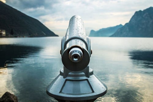 Image of telescope looking out on lake with mountains in the background